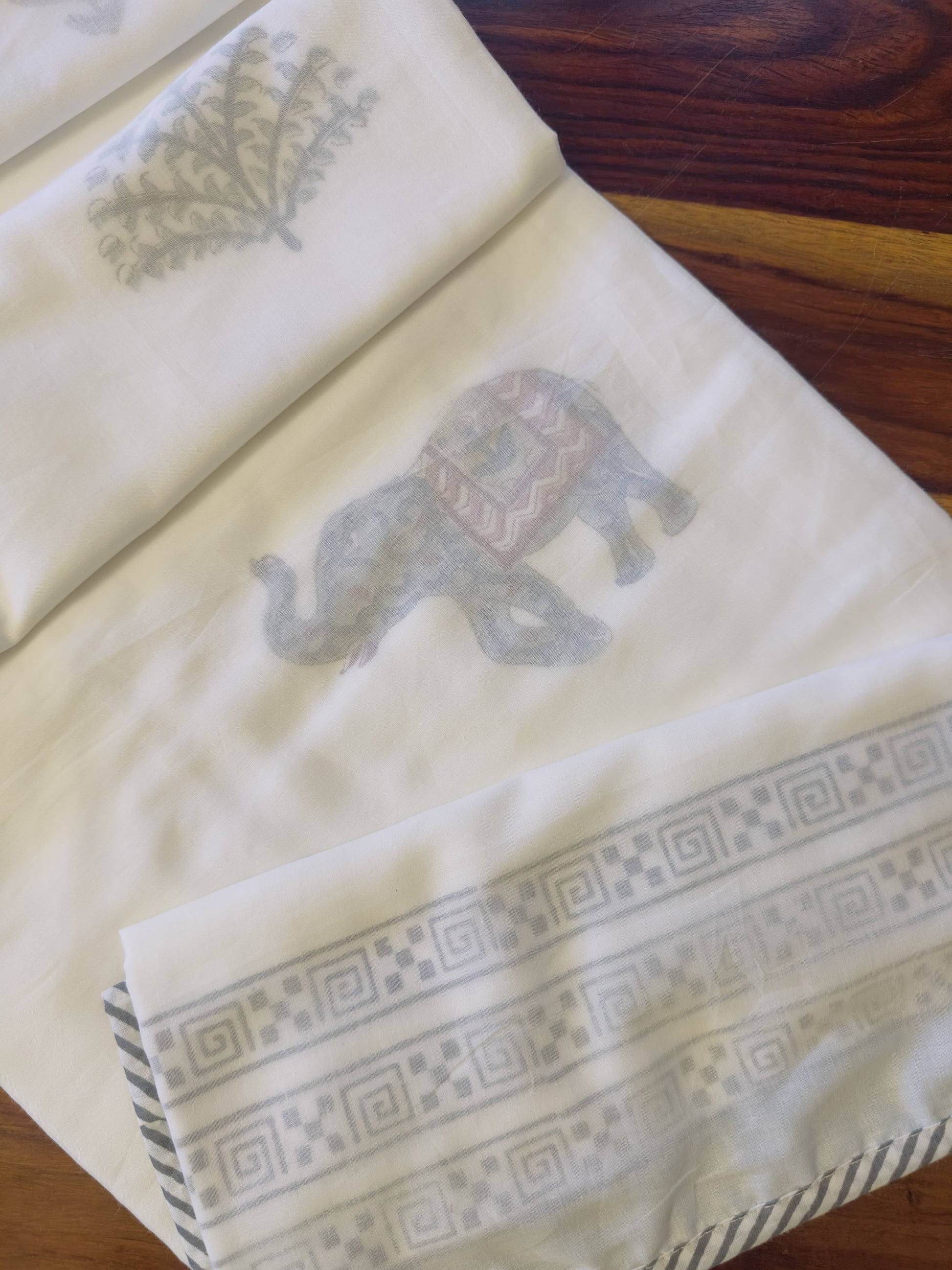 Folded Dohar with elephant design on a wooden surface