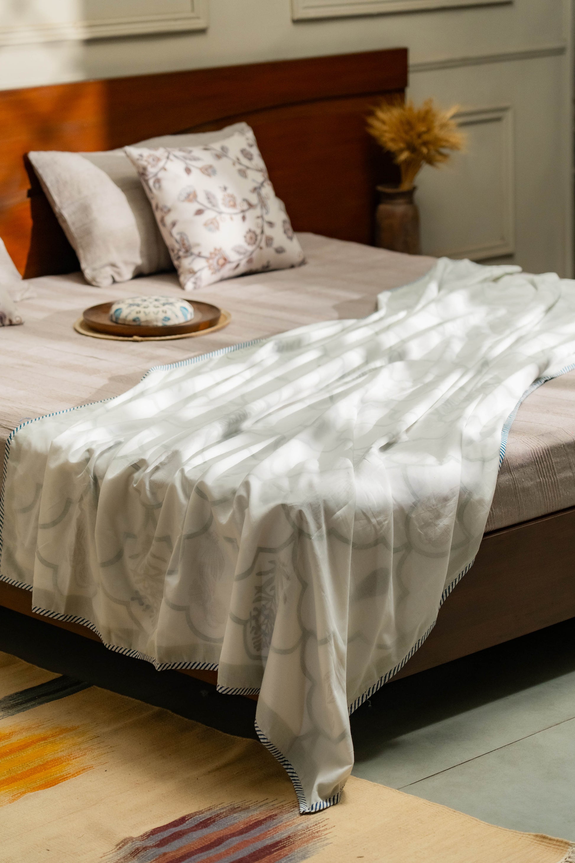 Bed with a white patterned blanket draped over it, in a bedroom setting.