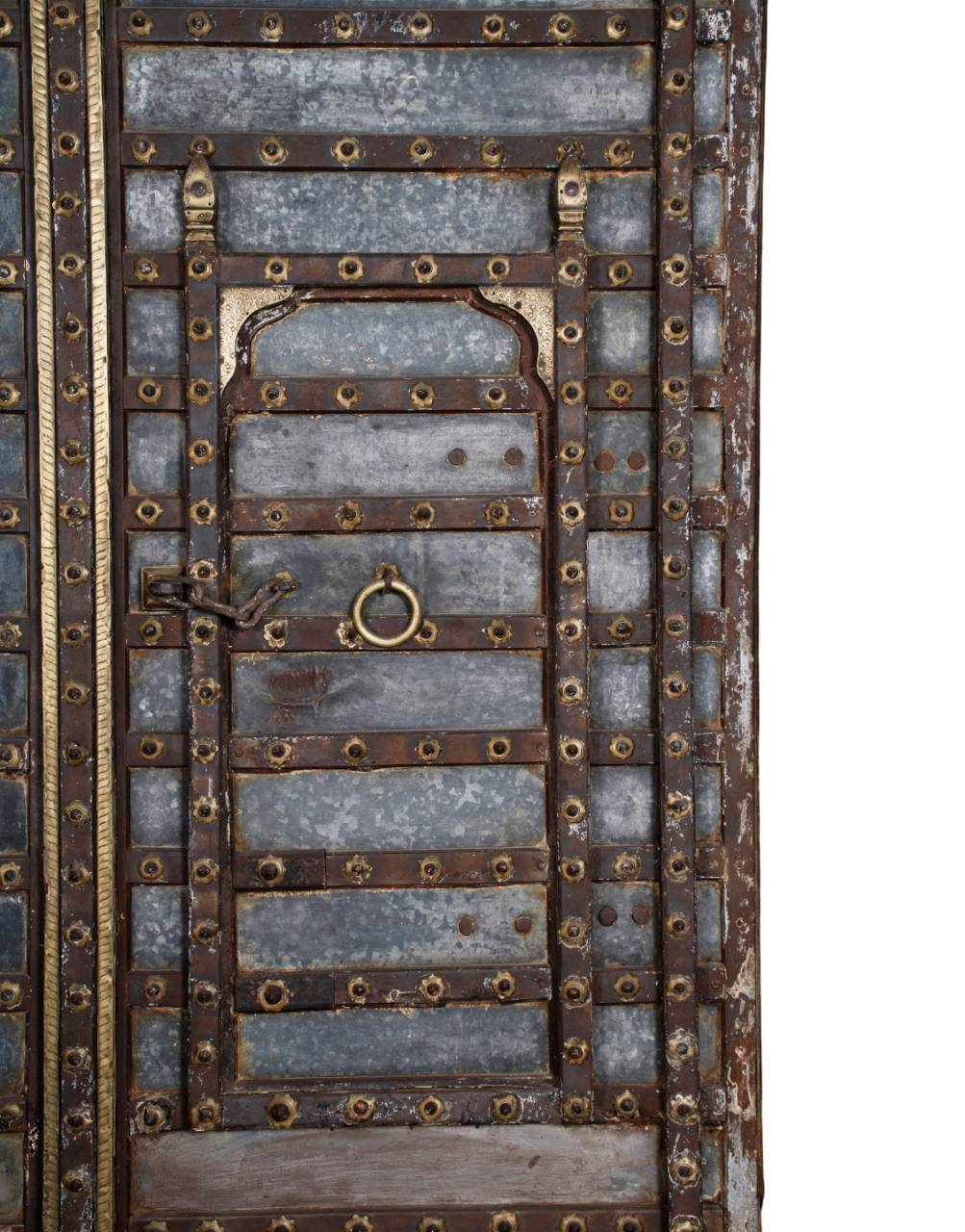 A close-up of an ornate traditional wooden door featuring weathered gray wood planks, dark brown metal crossbars, and numerous brass-colored rivets and decorative accents.
