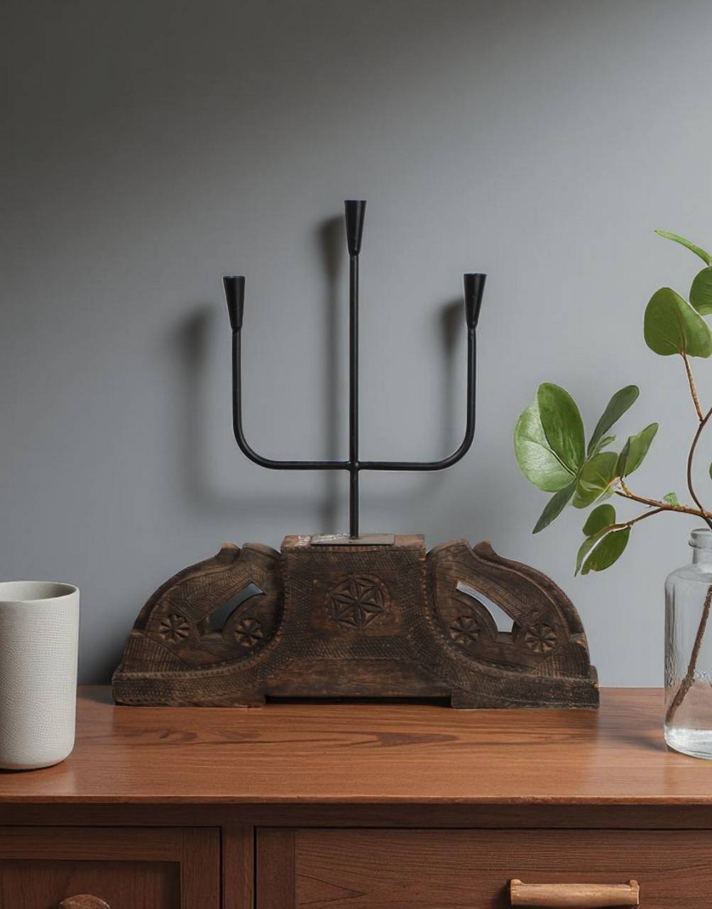 Decorative metal candelabra on a wooden surface with a gray wall background