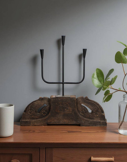 Decorative metal candelabra on a wooden surface with a gray wall background