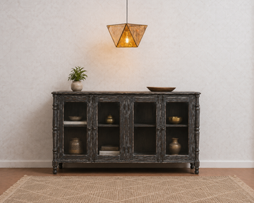 A dark gray distressed wood sideboard cabinet with glass doors, styled in a room setting with a hanging light fixture, a small potted plant, and decorative vases on top and inside.