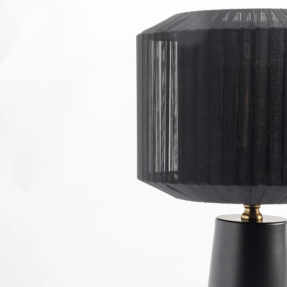 this lamp casts a warm, diffused glow that dances through its pleated texture, creating a mesmerizing play of light and shadow.