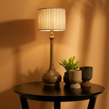 Decorative table lamp with a textured shade on a wooden surface against a warm beige wall.