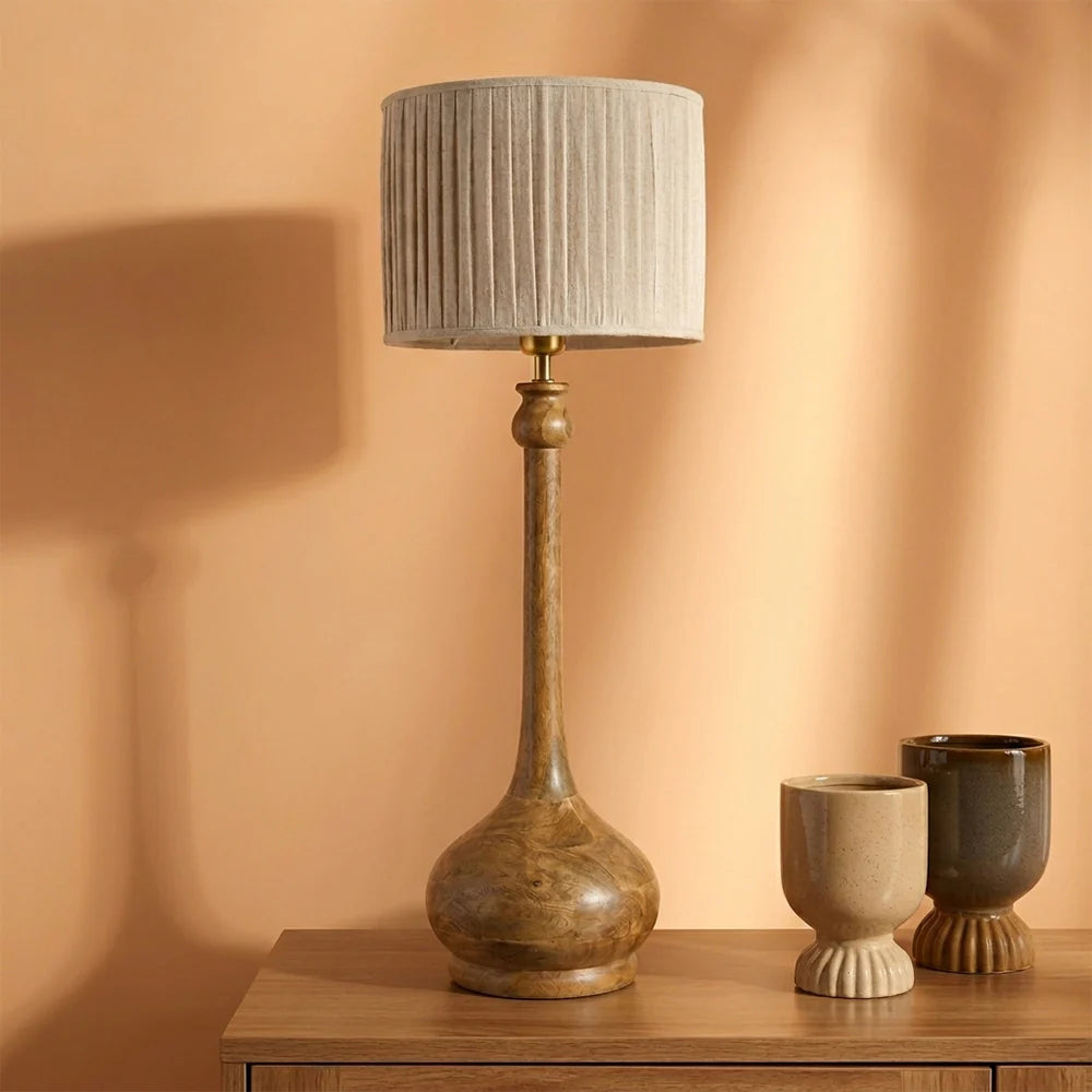 Table lamp with a textured shade on a wooden surface against an orange wall