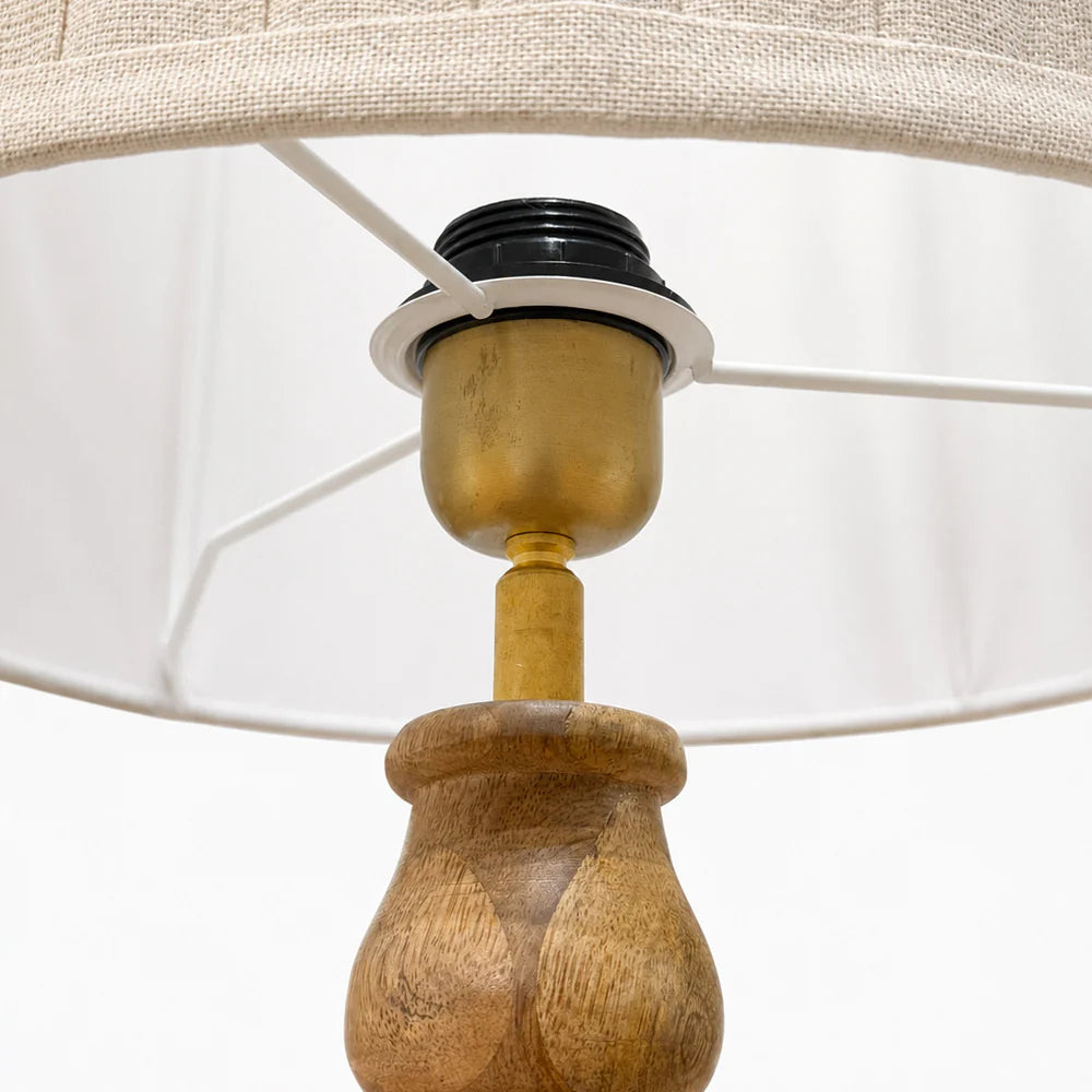 Close-up of a wooden lamp base with a beige lampshade on a white background