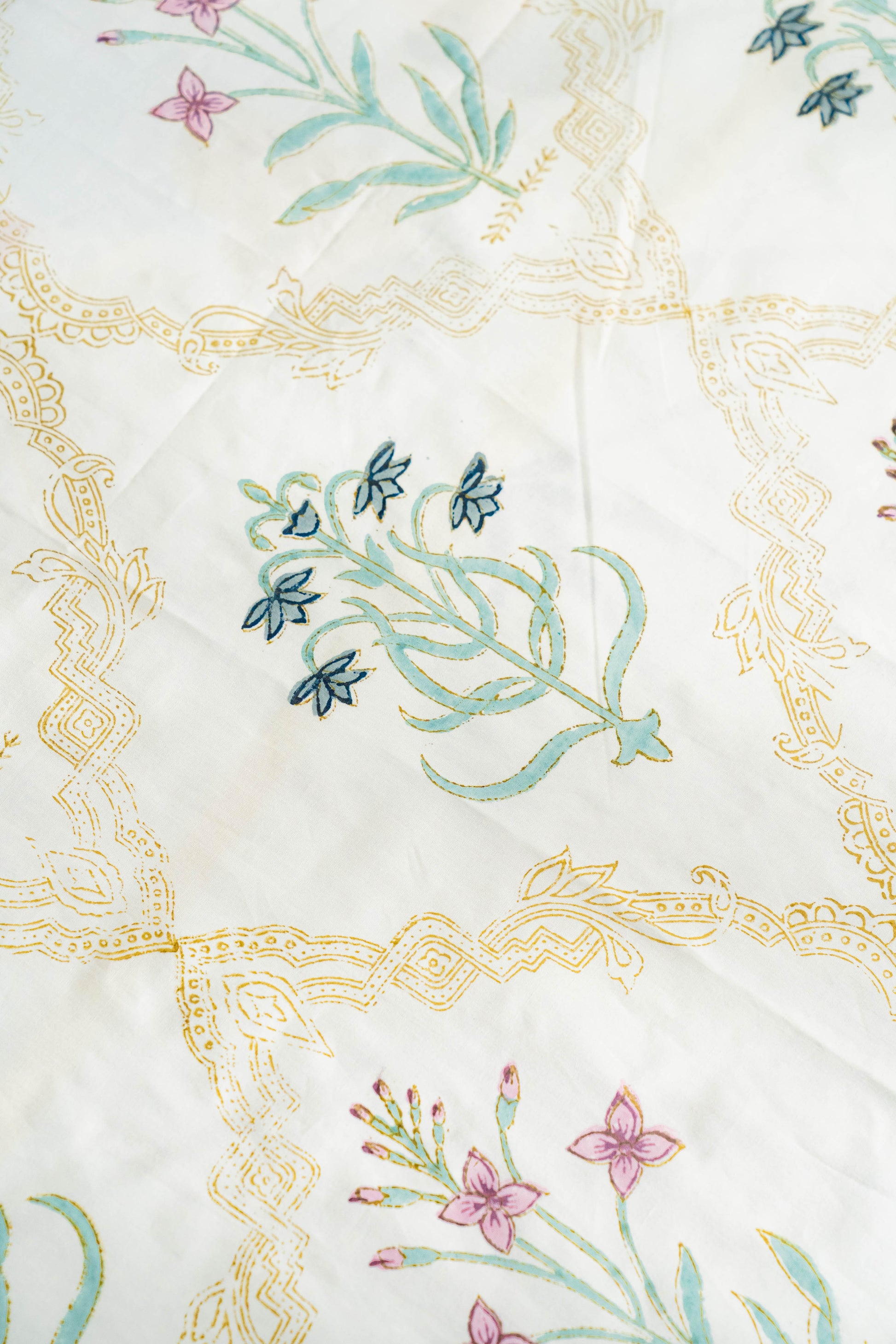 Embroidered fabric with floral patterns and gold borders on a white background