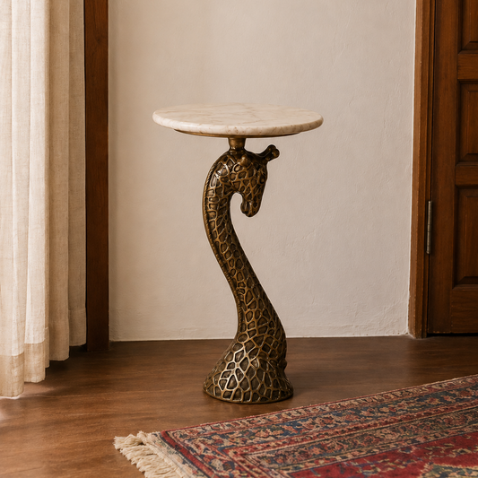 A decorative giraffe-shaped side table with a round white marble top and a textured bronze neck and base, set in a room with a wooden door, beige wall, patterned rug, and curtains.