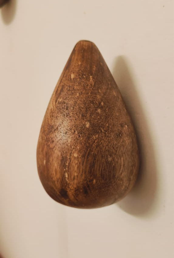 Teardrop-shaped wooden object on a plain background