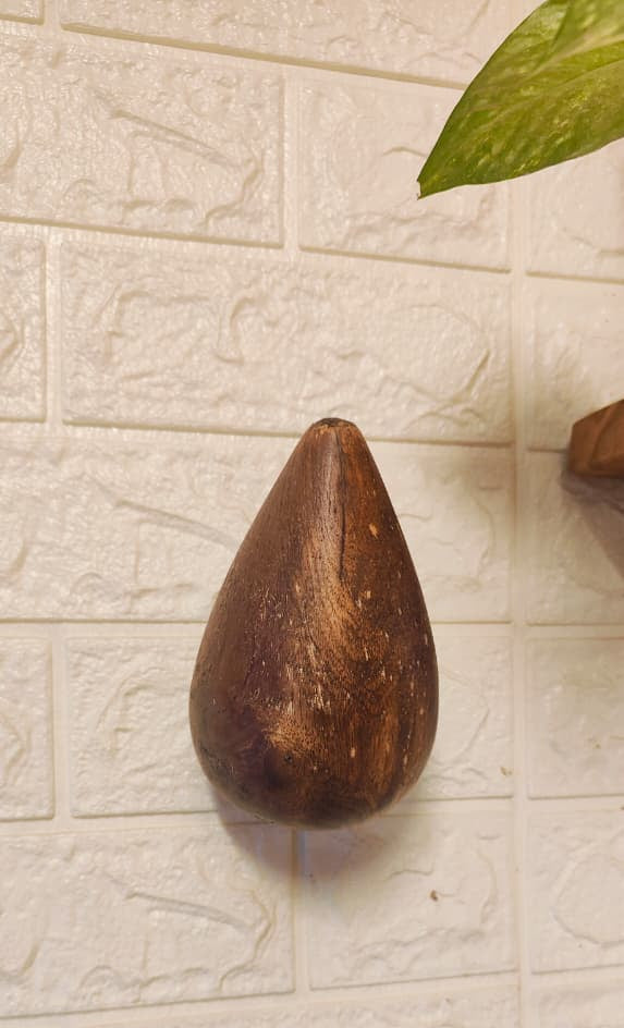 Wooden pear-shaped object on a textured beige wall