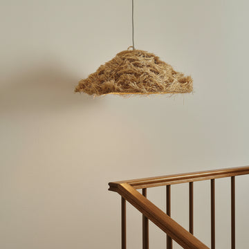 Textured pendant light hanging against a neutral wall