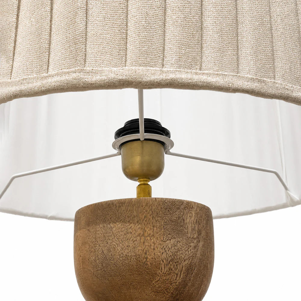 Close-up of a lamp with a wooden base and beige pleated shade on a white background