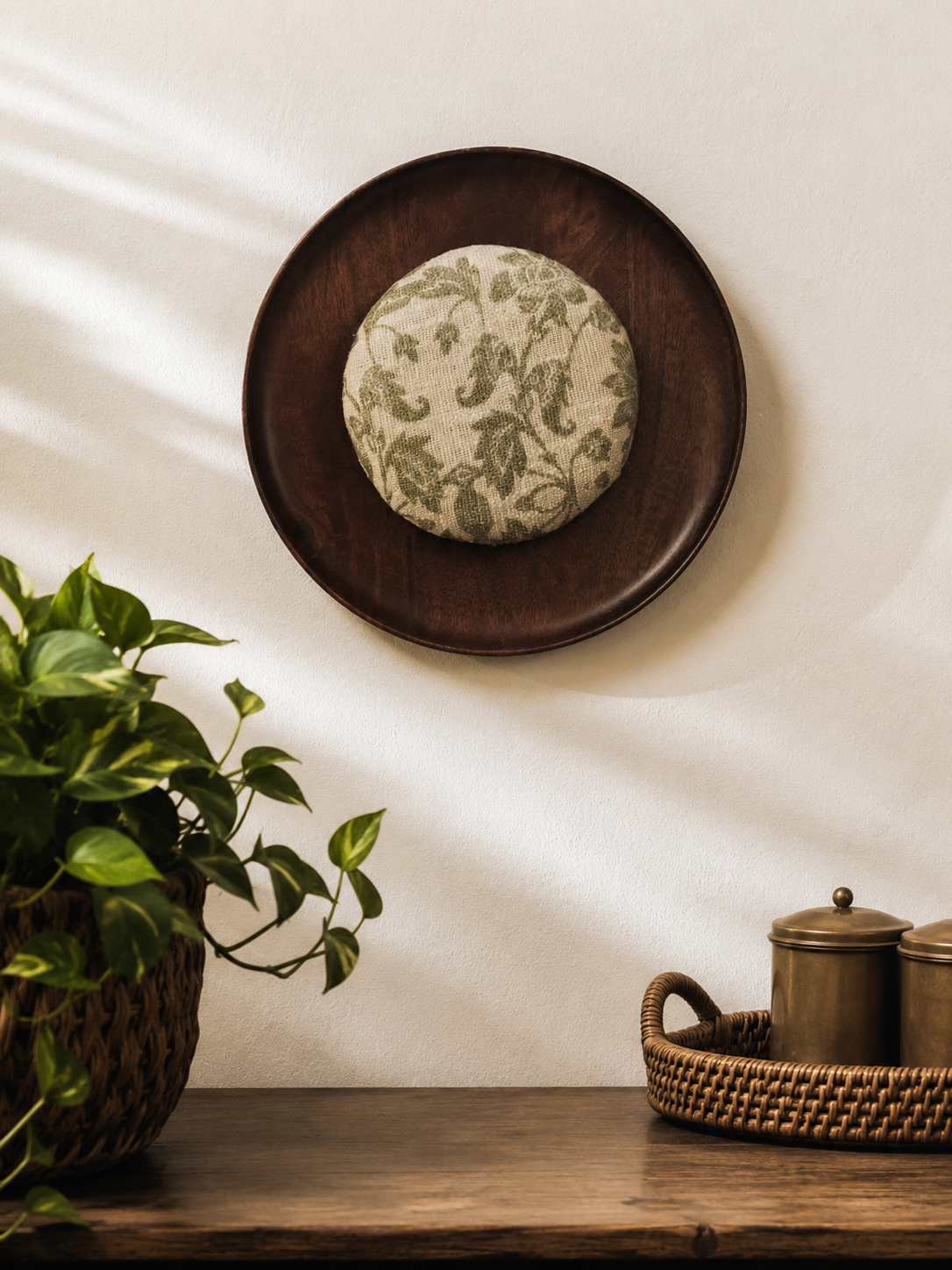 Decorative plate with floral design on a wooden surface next to a plant and basket.