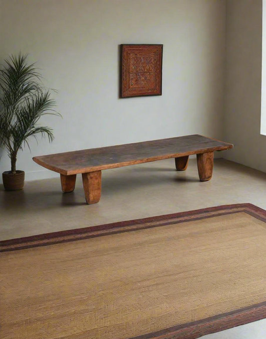 Wooden bench in a room with a plant and wall art