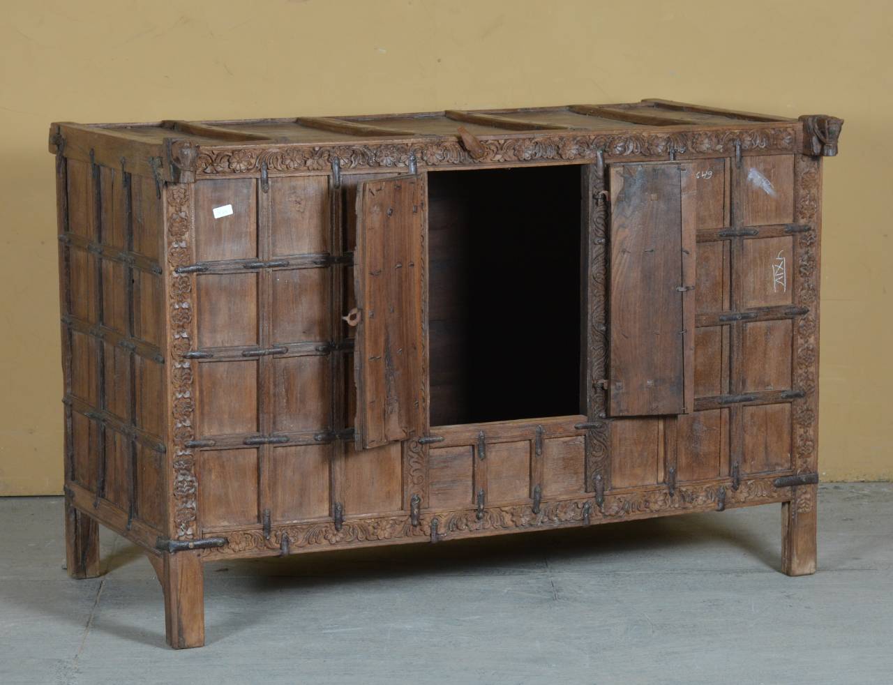 This antique storage chest features a bold grid-panel design with delicately hand-carved floral accents along the edges, reflecting the artisan’s deep respect for nature and craftsmanship. 