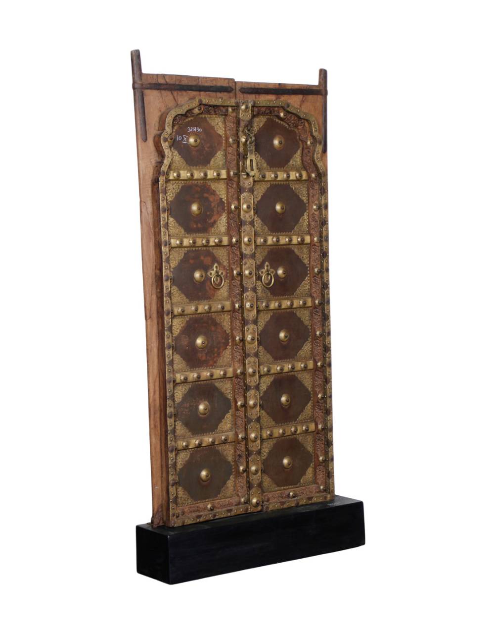 A decorative wooden door panel with ornate metal studs, circular medallions, and brass-toned hardware, mounted on a black rectangular base against a plain white background.