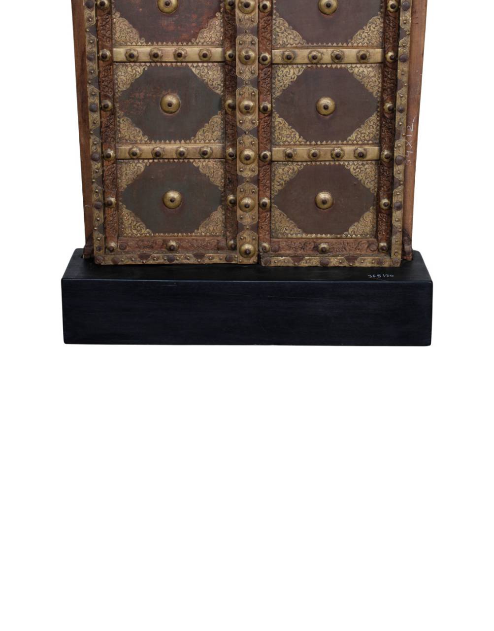 A close-up of a vintage-style metal cabinet or door with riveted panels in bronze, brown, and gold tones, mounted on a black base against a white background.
