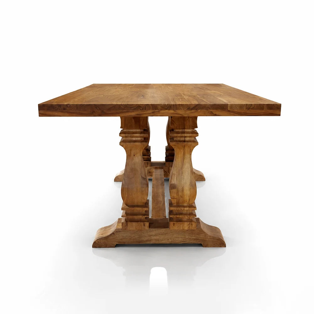 A rustic wooden dining table with a thick rectangular top and four carved pedestal legs, shown from a front angle on a white background.