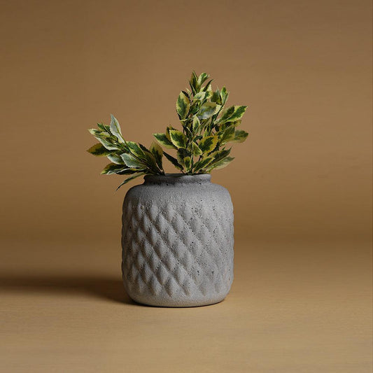 Gray textured vase with green leaves on a beige background