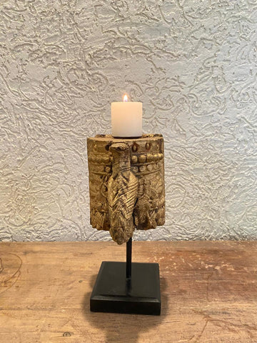 Decorative candle holder with a textured design on a wooden surface and light gray wall background