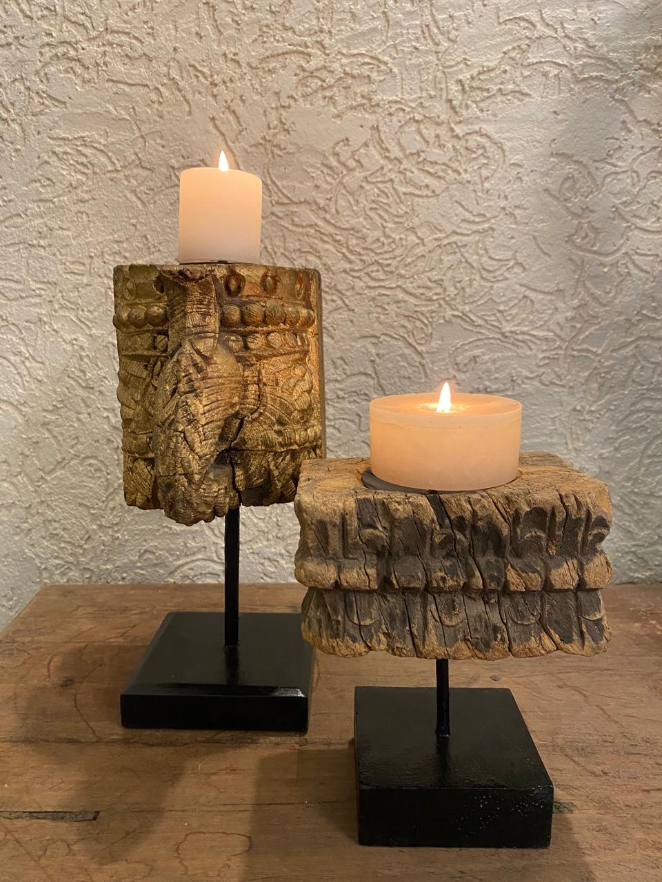 Two candle holders with candles on a textured wall background