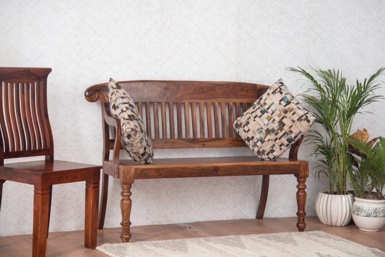  This handcrafted bench features a beautifully slatted backrest, curved armrests, and sturdy turned legs, adding a classic touch to any space. 