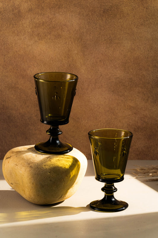 Two green glass goblets on a textured surface with a brown background