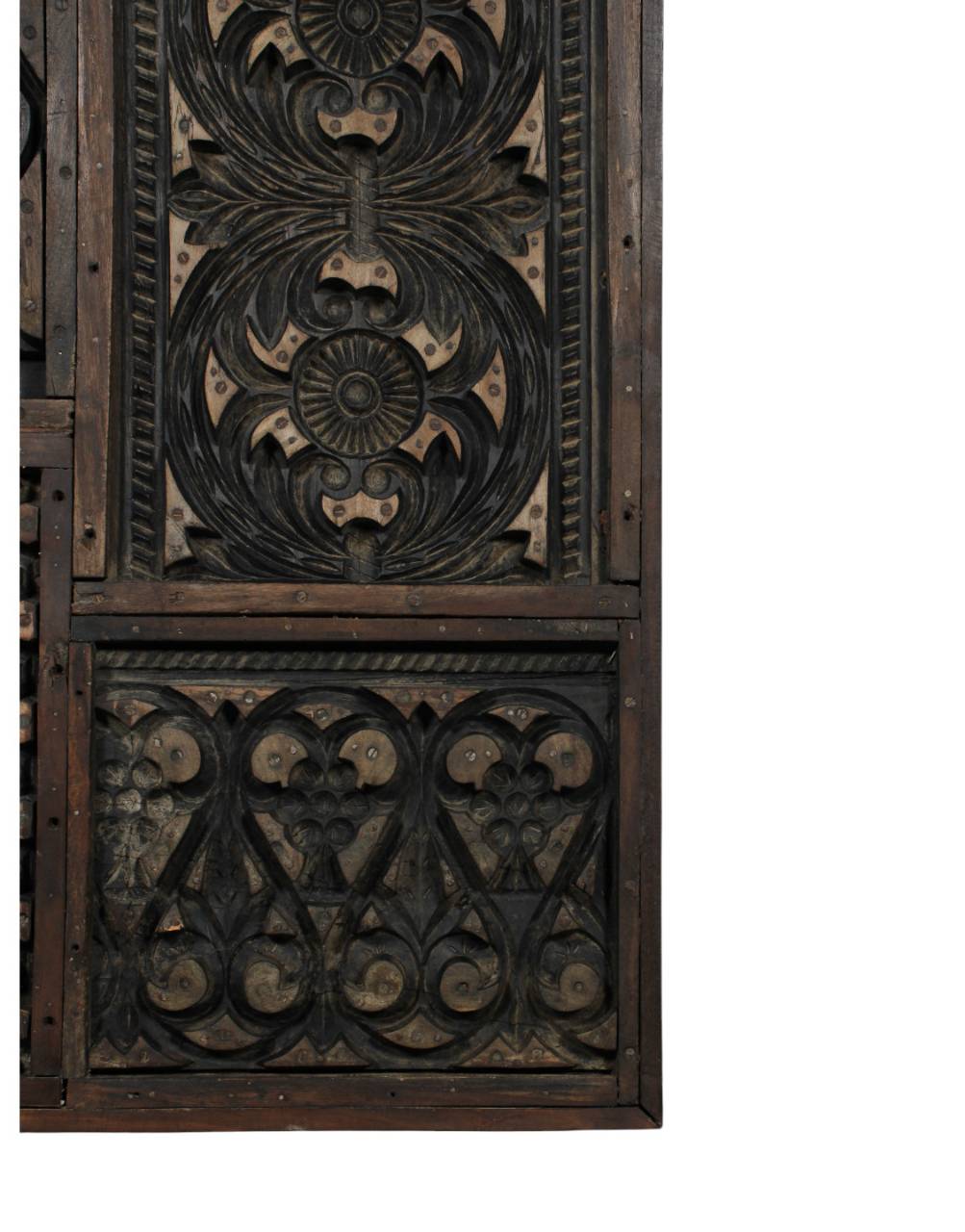 A close-up of an ornate carved wooden panel with dark stained black and brown details showing the natural wood underneath, set against a plain white background.