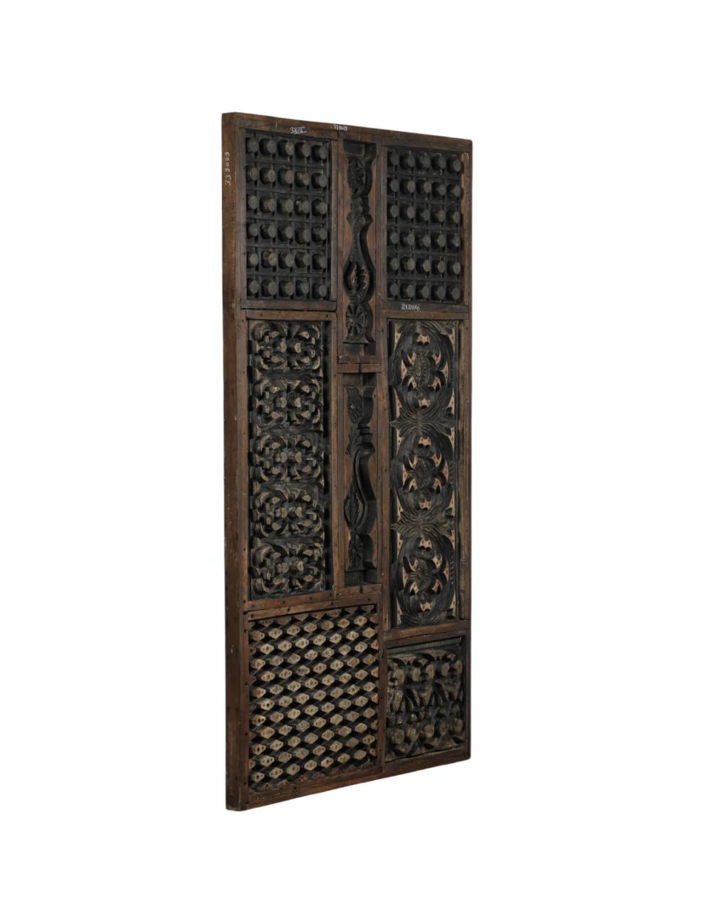 A tall, narrow dark carved wooden decorative panel with intricate geometric and floral patterns, shown against a plain white background.