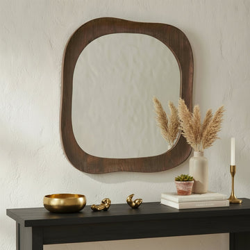 Wooden console table with decorative items and a large wooden-framed mirror on a textured wall.