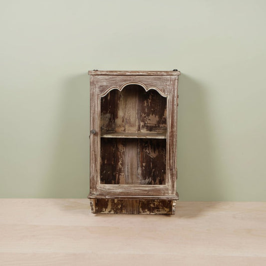 Vintage wooden cabinet with a distressed finish on a light green background
