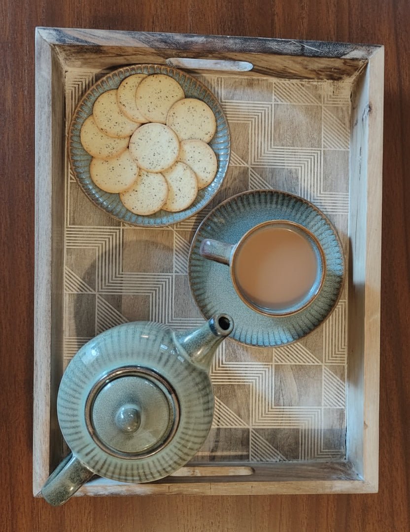 Tea set with teapot, cup, and cookies on a wooden tray
