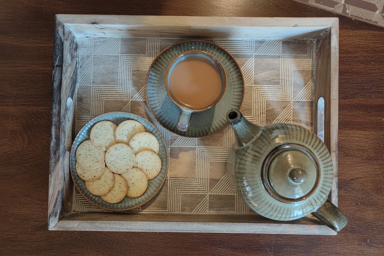 Tea set with a teacup, teapot, and cookies on a wooden tray.