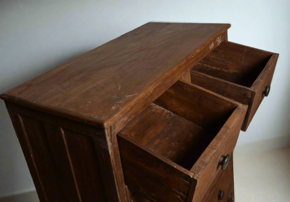 Wooden dresser with open drawers against a white wall