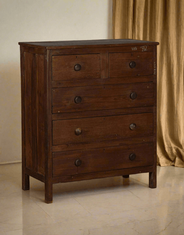 Wooden dresser with four drawers on a beige floor and wall background