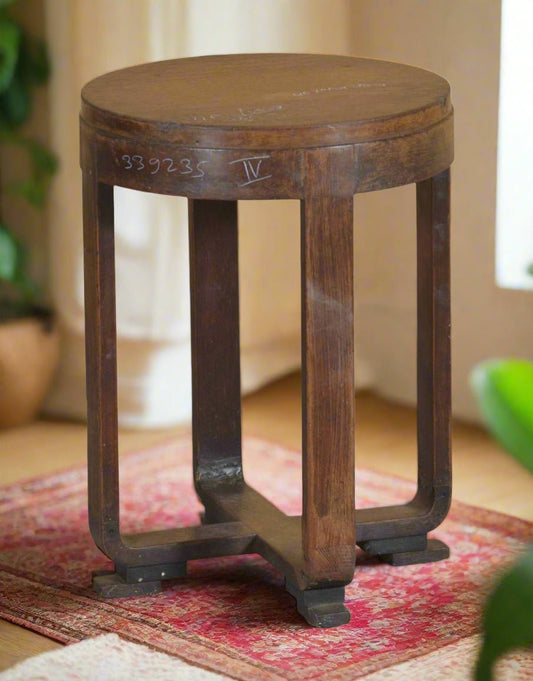 Wooden side table with a round top and four legs on a plain background