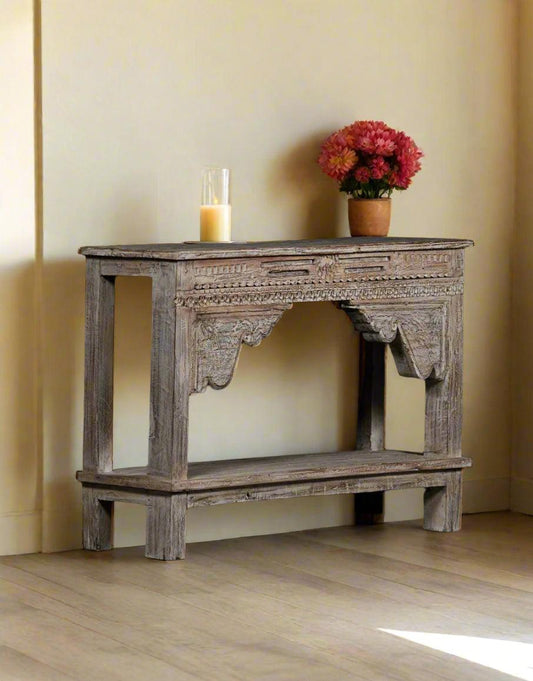 Wooden console table with decorative items against a plain wall