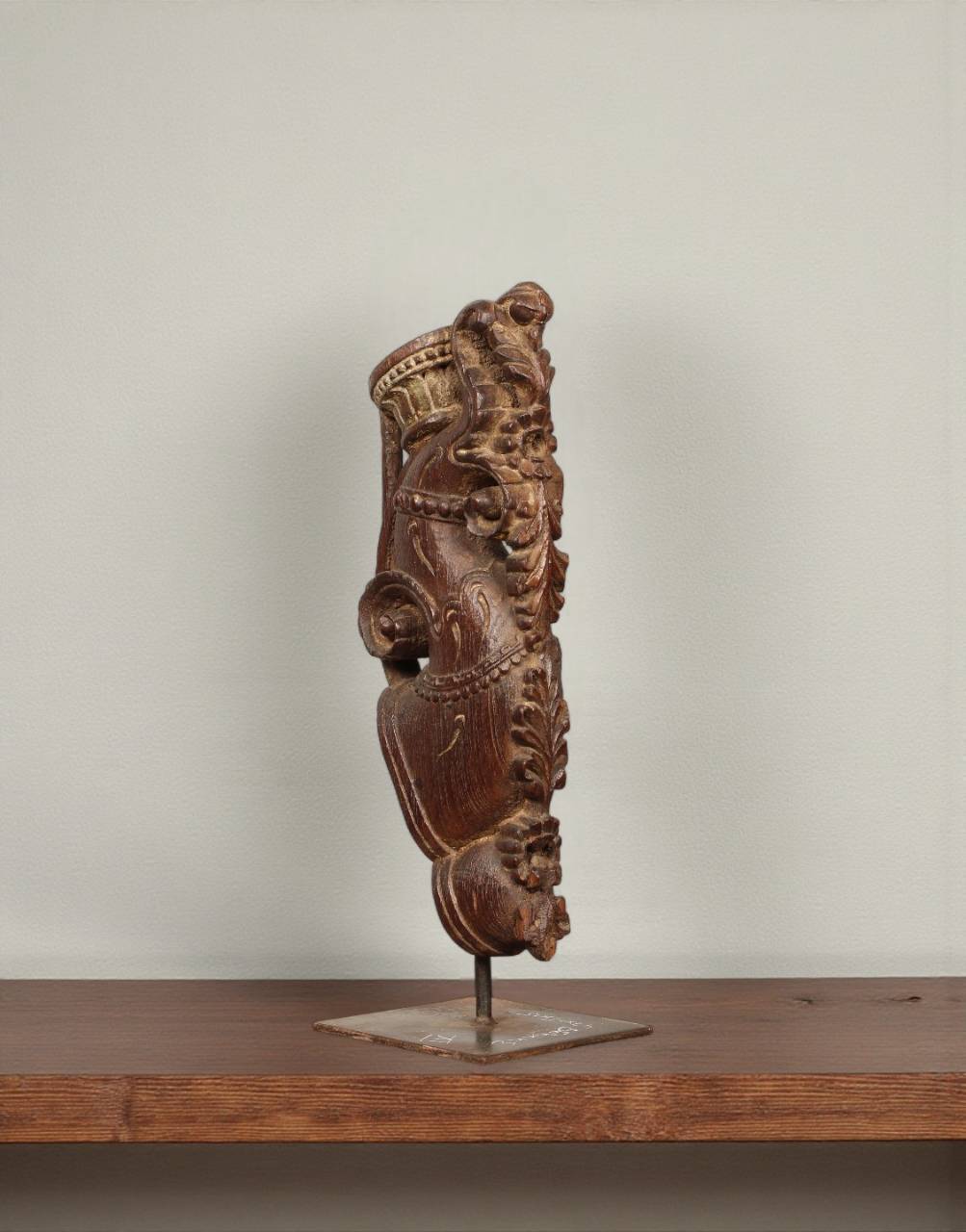 Decorative wooden sculpture on a stand against a plain background