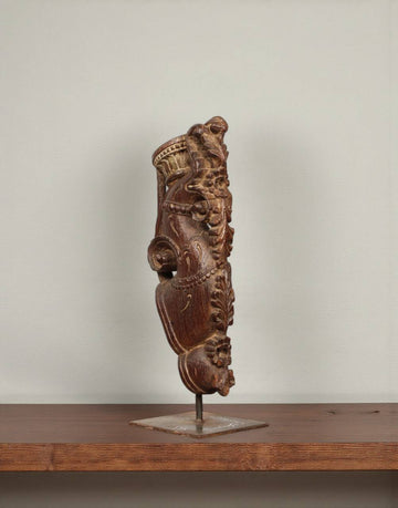 Decorative wooden sculpture on a stand against a plain background