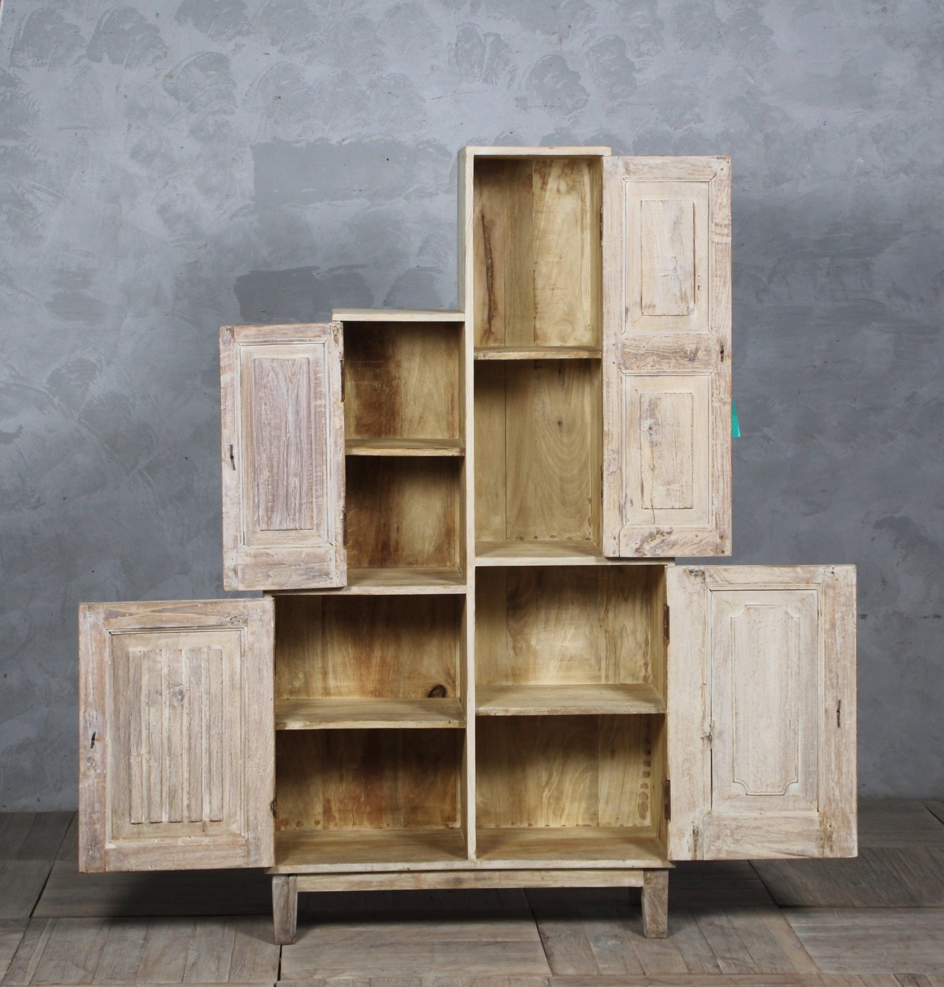 Set of wooden cabinets with open doors against a gray wall.