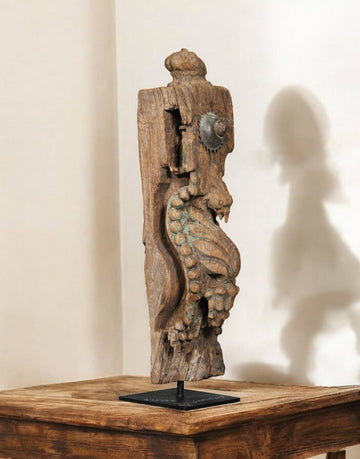 Wooden sculpture of a seahorse on a stand against a beige wall