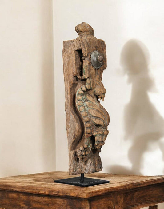Wooden sculpture of a seahorse on a stand against a beige wall