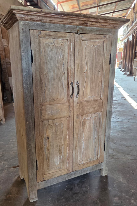 Vintage wooden cabinet with two doors in a storage or warehouse setting