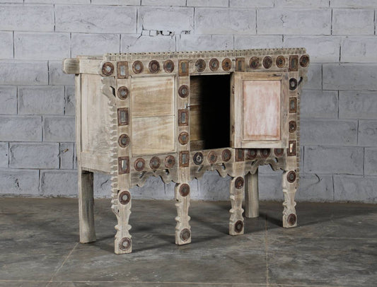 Wooden cabinet with decorative patterns against a gray brick wall.