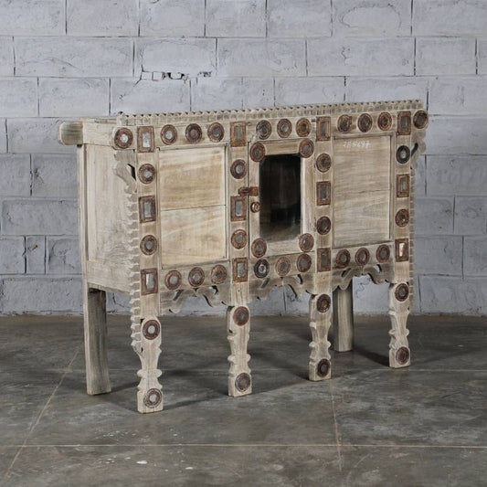 Wooden cabinet with decorative patterns against a gray brick wall.