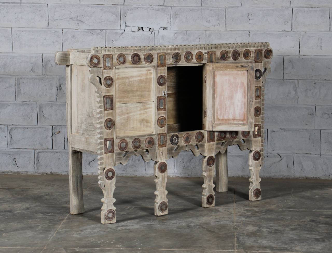 Wooden cabinet with decorative patterns against a gray brick wall.
