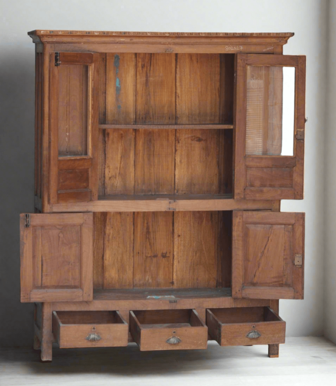 Wooden cabinet with open doors and drawers on a white floor.