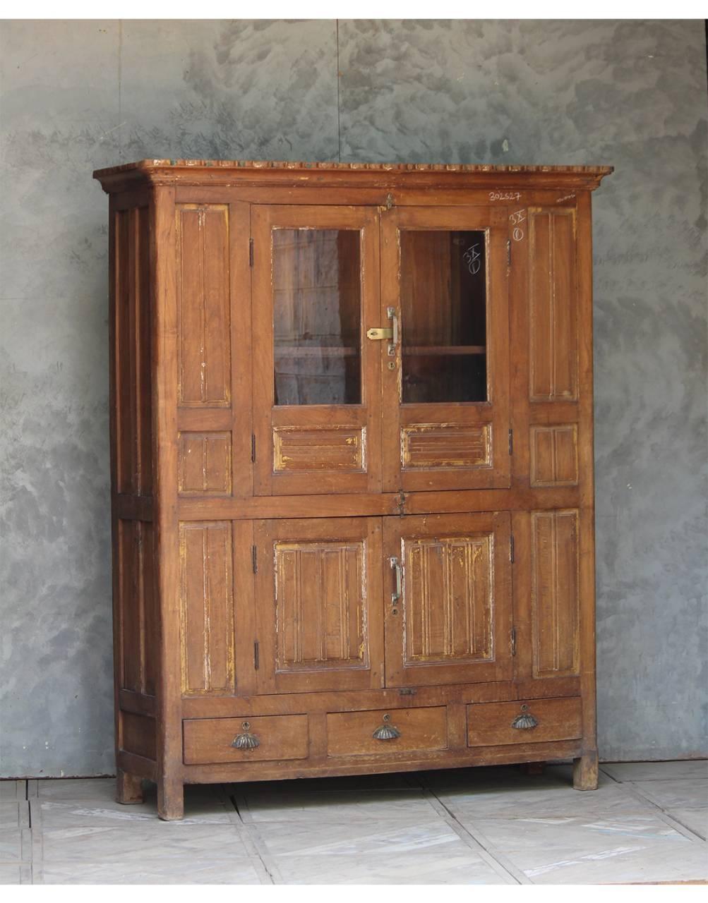 Wooden cabinet with glass doors against a textured wall.