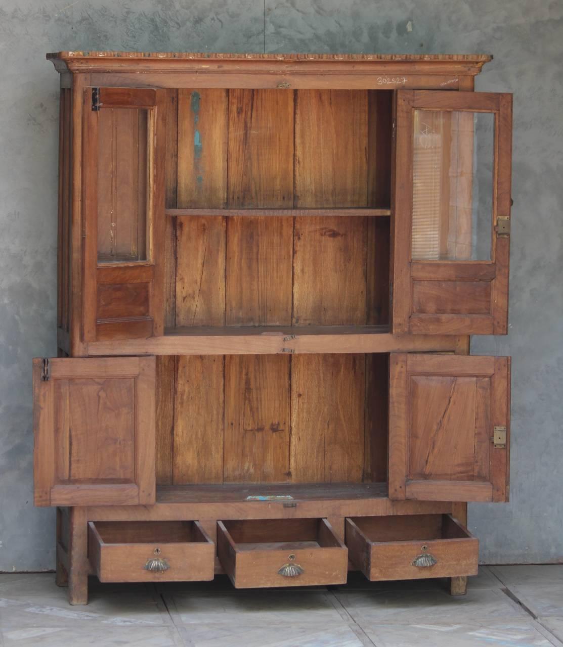 Wooden cabinet with open doors and drawers against a gray wall.