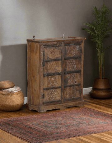 Wooden cabinet with decorative patterns in a room with a plant and rug.